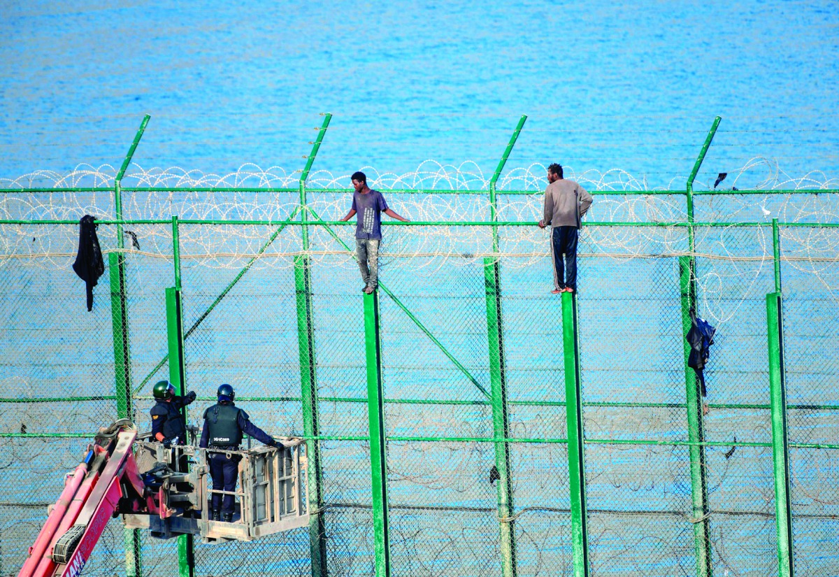 Two migrants force their way into the Spanish territory of Ceuta on August 30, 2018. Over 150 migrants made their way into Ceuta after storming a barbed-wire border fence with Morocco. AFP / Antonio Sempere