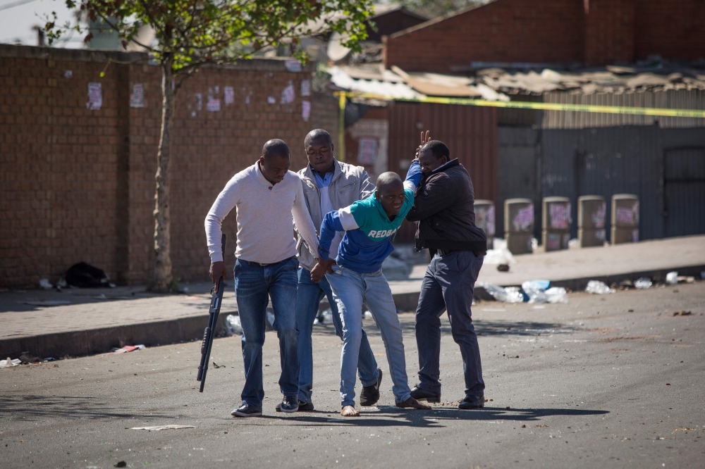South African police officers detain a looter in the Johannesburg township of Alexandra on September 3, 2019 after South Africa's financial capital was hit by a new wave of anti-foreigner violence.  AFP / GUILLEM SARTORIO
