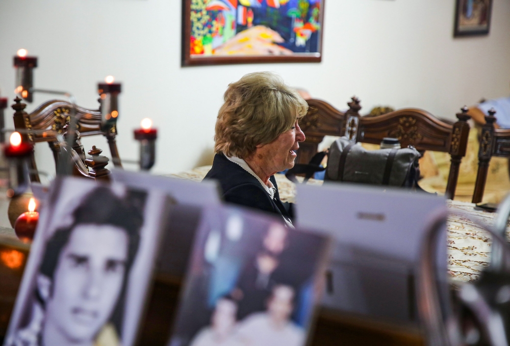 Samya Khasro, a woman from Iraq's once-persecuted Shiite Kurdish minority, sits next to pictures of family members who vanished 35 years prior and whose whereabouts remain unknown, as she gives an interview with AFP at her home in the capital Baghdad's hi