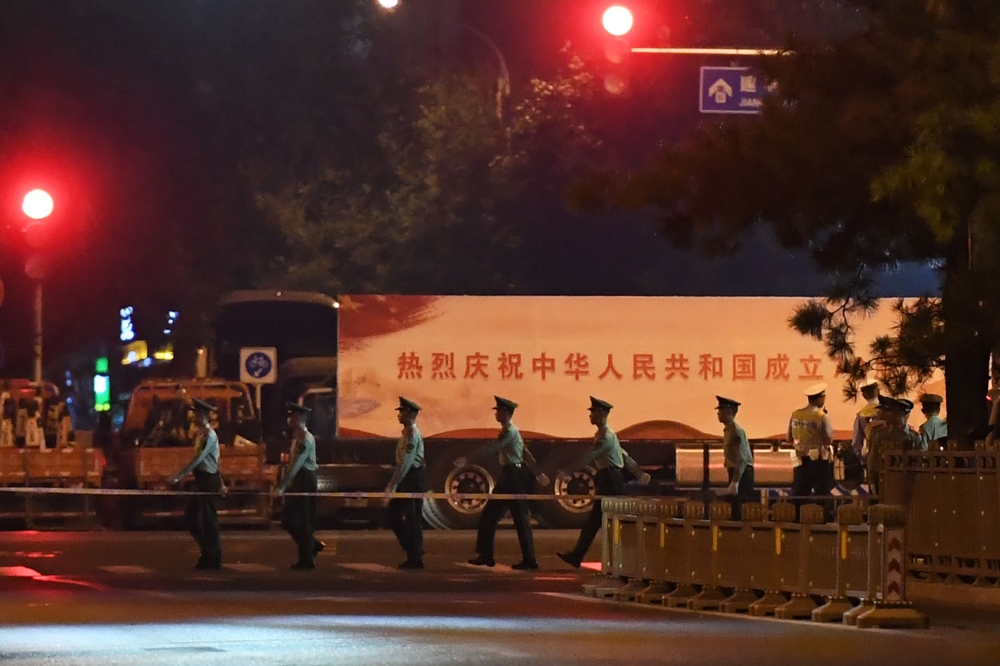 Paramilitary police march past trucks with propaganda slogans on Beijing's Changan Avenue, the city's main east-west boulevarde, during an overnight rehearsal of a military parade to mark Communist China's 70th anniversary, in Beijing on September 7, 2019