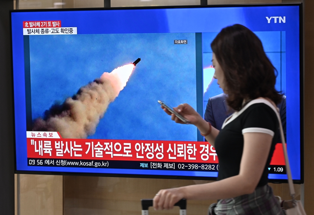 A woman walks past a television news screen showing file footage of a North Korean missile launch, at a railway station in Seoul on September 10, 2019. AFP / Jung Yeon-je