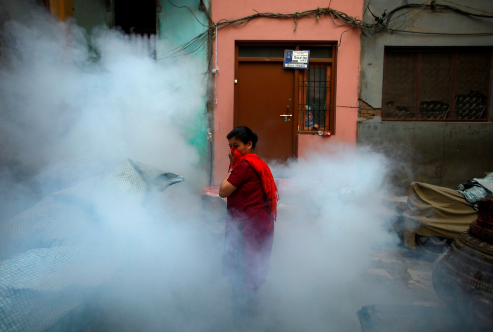 A woman covers her face as she walks away after a worker fumigated a resident area to prevent the spread of the dengue fever and other mosquito-borne diseases in Kathmandu, Nepal September 5, 2019. Reuters/Navesh Chitrakar
 