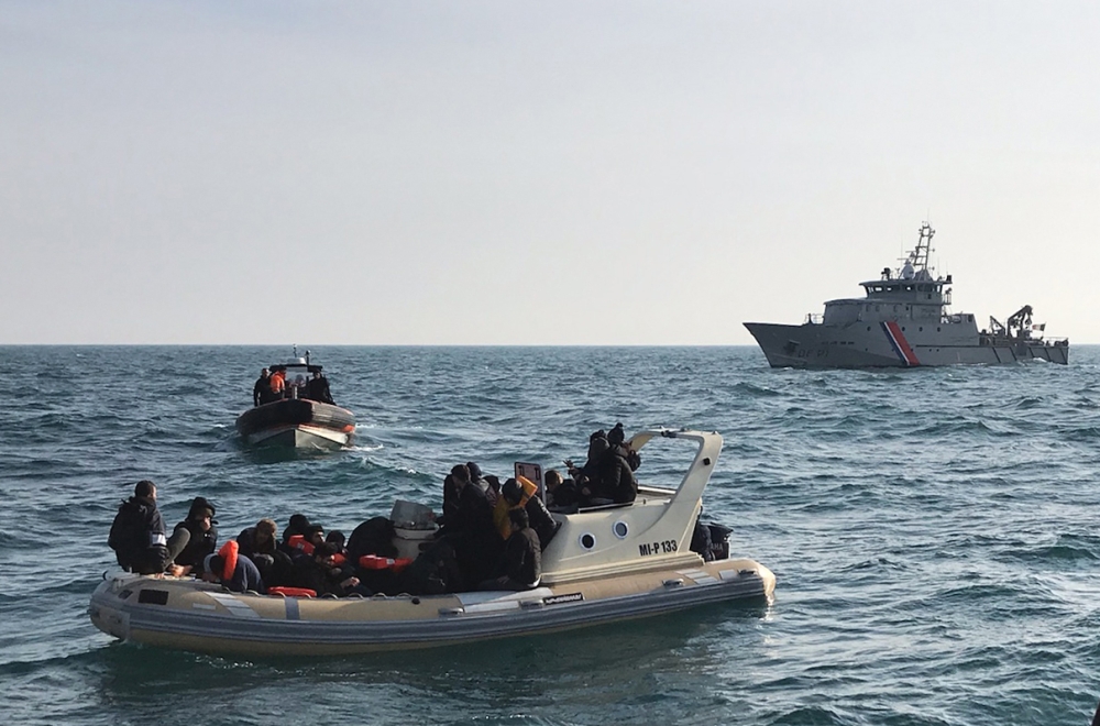 In this file photo taken on February 18, 2019, a handout image made available by France's Societe Nationale de Sauvetage en Mer (SNSM) on February 18, 2019, shows British rescuers (front) helping some 20 migrants on a semi-rigid boat trying make their way
