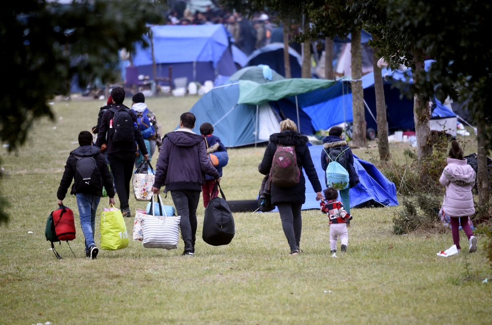 People and children leave after the evacuation, by French gendarmes, of the Grande Synthe migrant camp, northern France, on September 17, 2019. / AFP / FRANCOIS LO PRESTI 