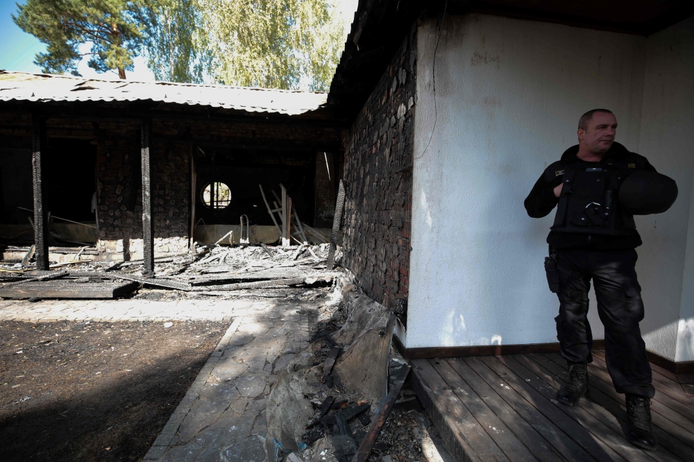 Security guards stand next to the burnt country home of former Central Bank chief Valeria Gontareva in a village north of Kiev, on September 17, 2019. AFP
 