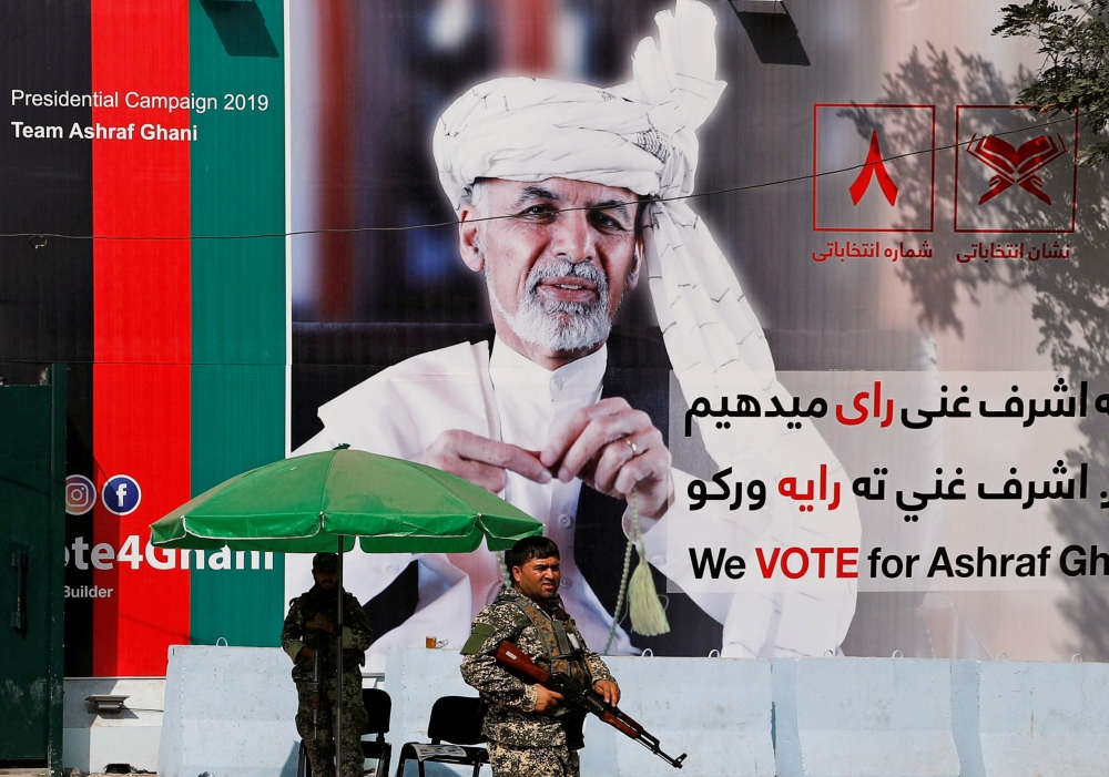 FILE PHOTO: A member of the Afghan security force stands in front of a poster of Afghan presidential candidate Ashraf Ghani in Kabul, Afghanistan September 2, 2019. REUTERS/Mohammad Ismail/File Photo