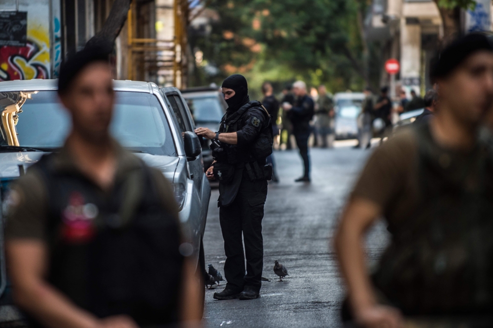 (FILES) In this file photo taken on August 26, 2019 Police officers stand guard outside a building during an evacuation operation, in the Exarchia district, central Athens. AFP / ANGELOS TZORTZINIS