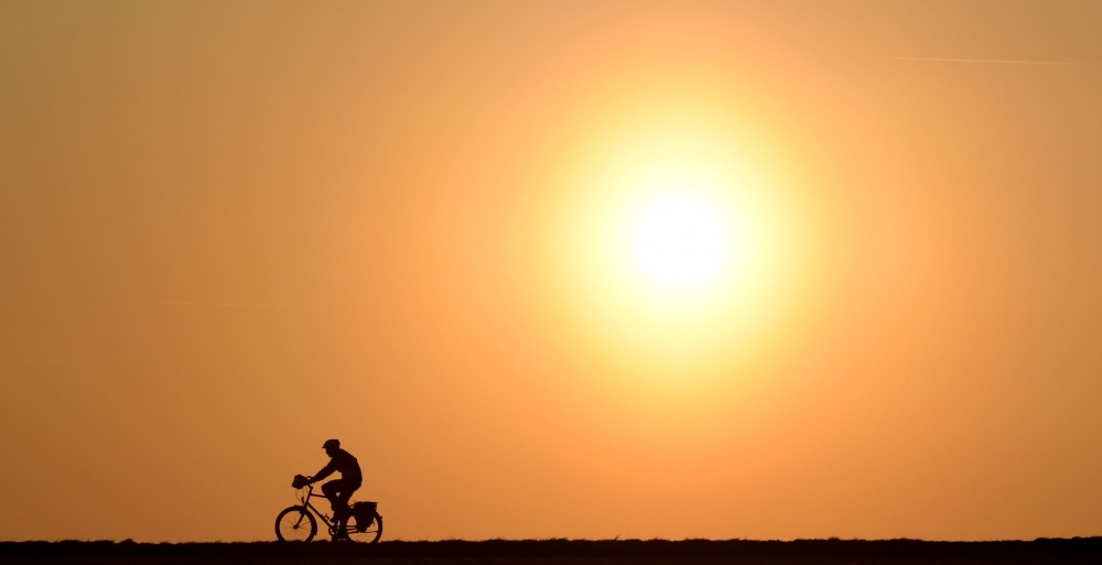 A cyclist passes a street near the village of Pflaumdorf, southern Germany during sunset on February 28, 2019. AFP/Christof Stache