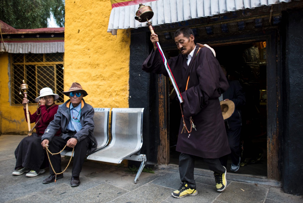 A pilgrim spinning his prayer wheel in front of the Thousand Buddha Cliffside Sculpture on September 10, 2016 in the regional capital Lhasa in Tibet Autonomous Region of China. (AFP / Johannes Eisele) 