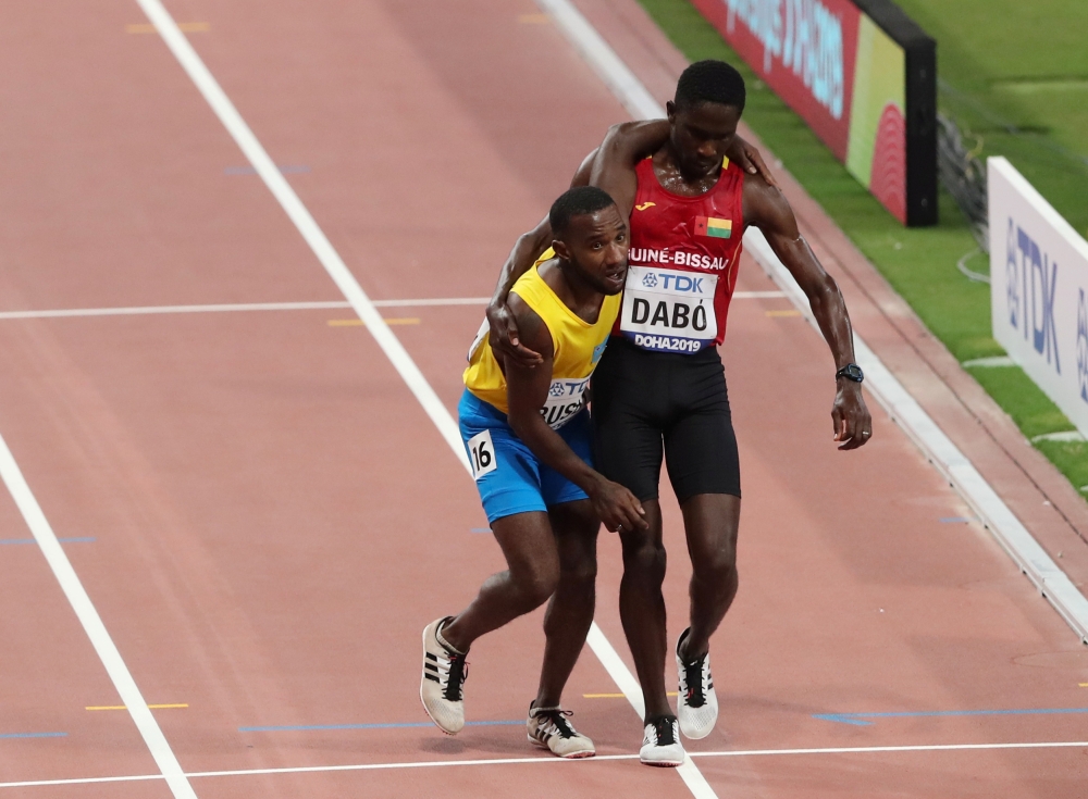 Aruba's Jonathan Busby is helped to the finish line by Guinea-Bissau's Braima Suncar Dabo REUTERS/Ahmed Jadallah