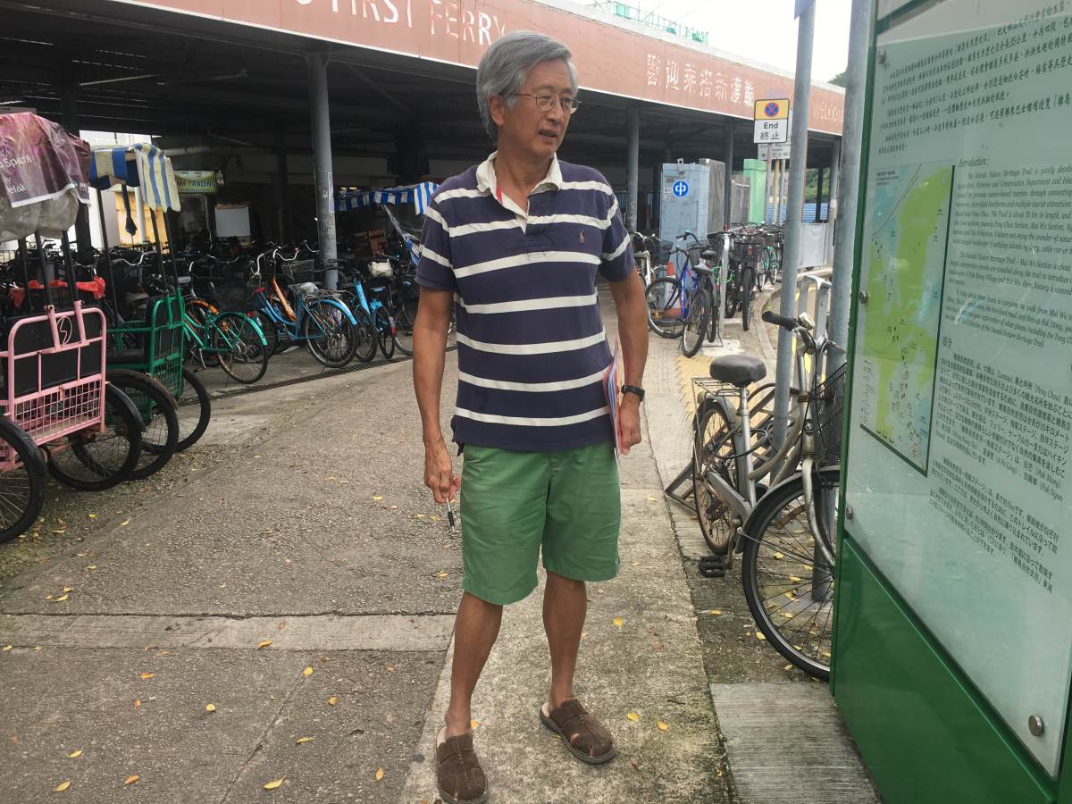 Tom Yam, a resident of Lantau Island, stands in front of a map of the island, whose landscape may be changed with a plan to build artificial islands to ease congestion in Hong Kong. August 6, 2019. Thomson Reuters Foundation/Rina Chandran