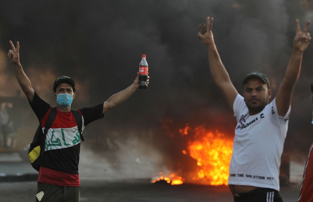 Iraqi demonstrators gesture next to a tyre fire during a demonstration against state corruption, failing public services, and unemployment, in the Iraqi capital Baghdad on October 5, 2019. AFP / AHMAD AL-RUBAYE