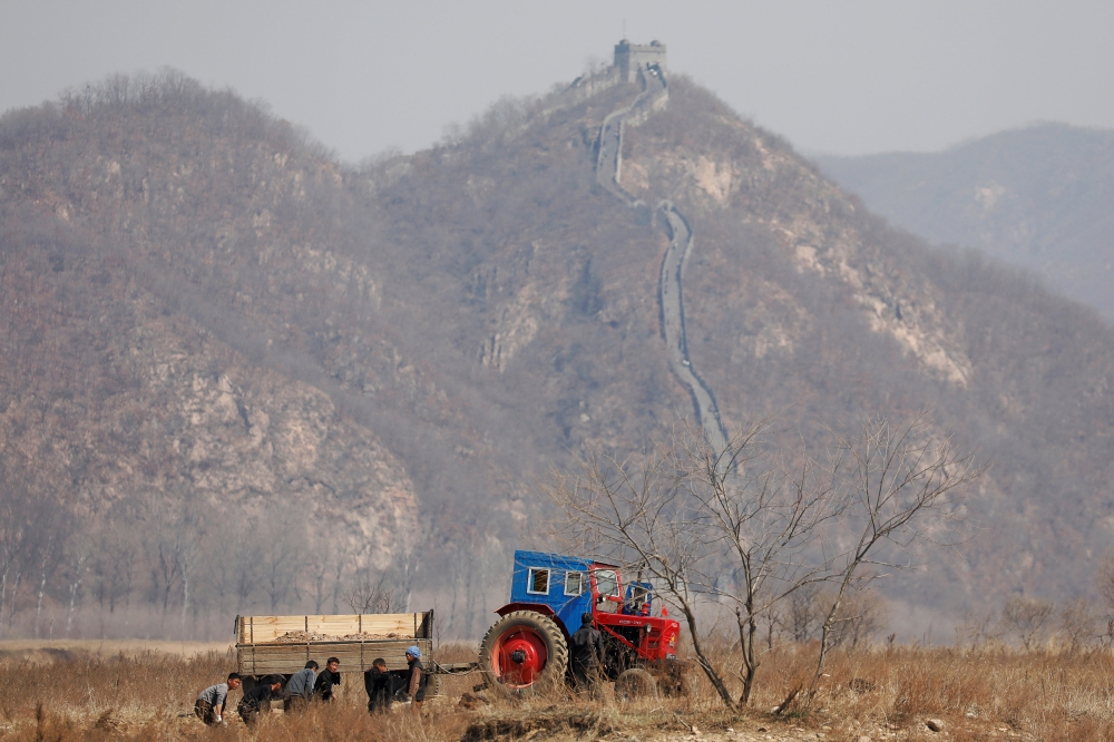 Farmers in a field as a section of the Great Wall is seen on the Chinese side of the Yalu River north of the town of Sinuiju in North Korea and Dandong in Chinese Liaoning province, April 2, 2017. Reuters / Damir Sagolj