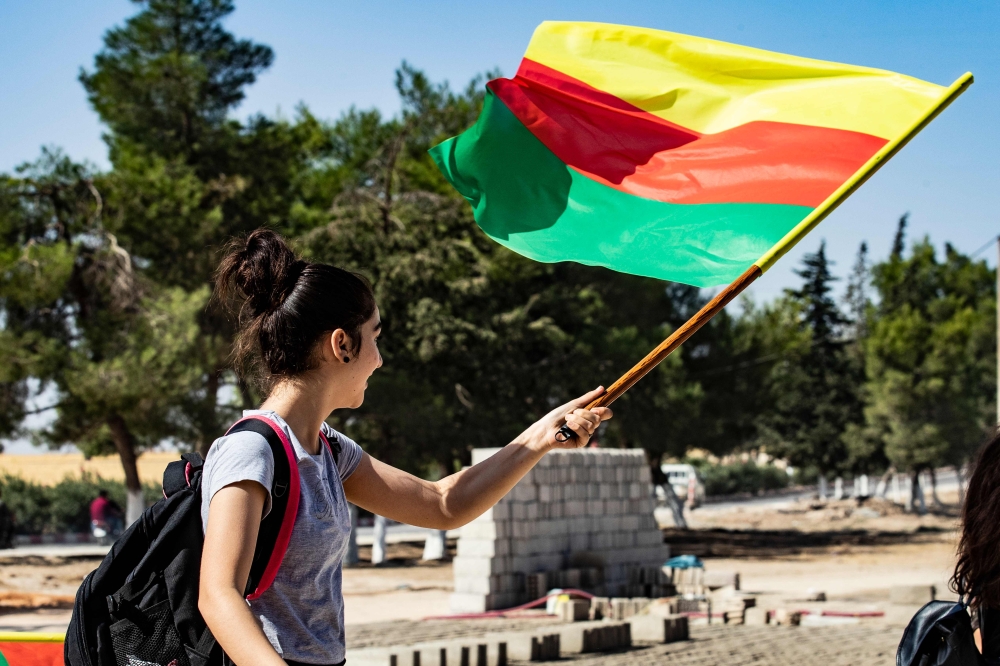 A young girl waves the flag of Kurdistan during a demonstration by Syrian Kurds against Turkish threats to launch a military operation on their region, in the town of Al-Qahtaniyah, in northeastern Syrian Al-Hasakah Governorate on October 7, 2019. AFP / D