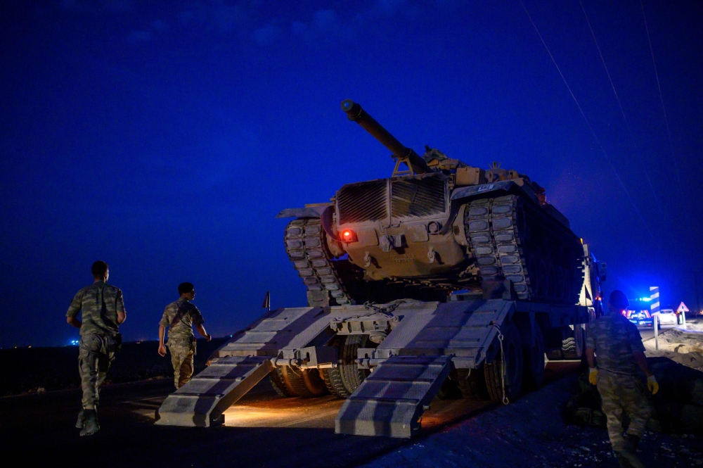 A Turkish army's tank drives down from a truck as Turkish armed forces drive towards the border with Syria near Akcakale in Sanliurfa province on October 8, 2019. AFP / BULENT KILIC