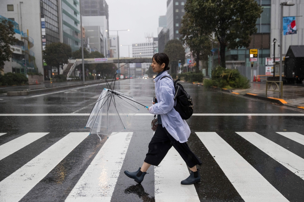 A pedestrian with a broken umbrella braves the elements in the Aoyama district of Tokyo on October 12, 2019, as the effects of Typhoon Hagibis begin to be felt in Japan's capital. (AFP / Odd ANDERSEN)