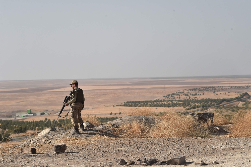A Turkish soldier overlooks the border with Syria on Ocotber 13, 2019 near the Turkish city of Ceylanpinar as fighting rages in the Syrian border town of Ras al-Ain on the fifth day of the Turkish offensive in Syria against the Kurdish People's Protection