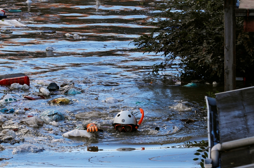 A rescue worker swims as he checks around a flooded residential area due to Typhoon Hagibis, in Kawasaki, Japan, October 13, 2019. REUTERS/Kim Kyung-Hoon 