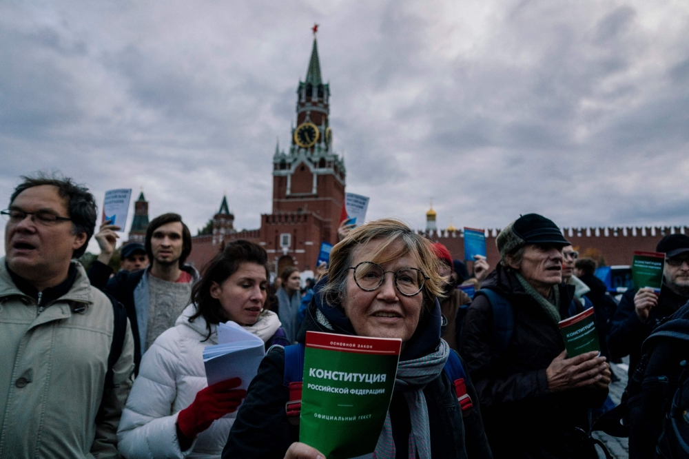 Opposition supporters holding the Russian Constitution books walk on Red Square to support opposition activist Konstantin Kotov, who was sentenced to four years in prison for repeatedly taking part in unauthorised rallies, in downtown Moscow on October 13