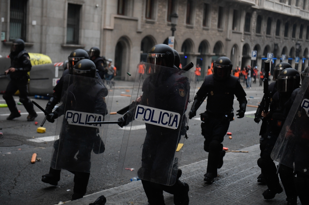 Police officers intervene in protesters during clashes near the Police headquarters in Barcelona, on October 18, 2019, on the day that separatists have called a general strike and a mass rally. (Adria Puig - Anadolu Agency)