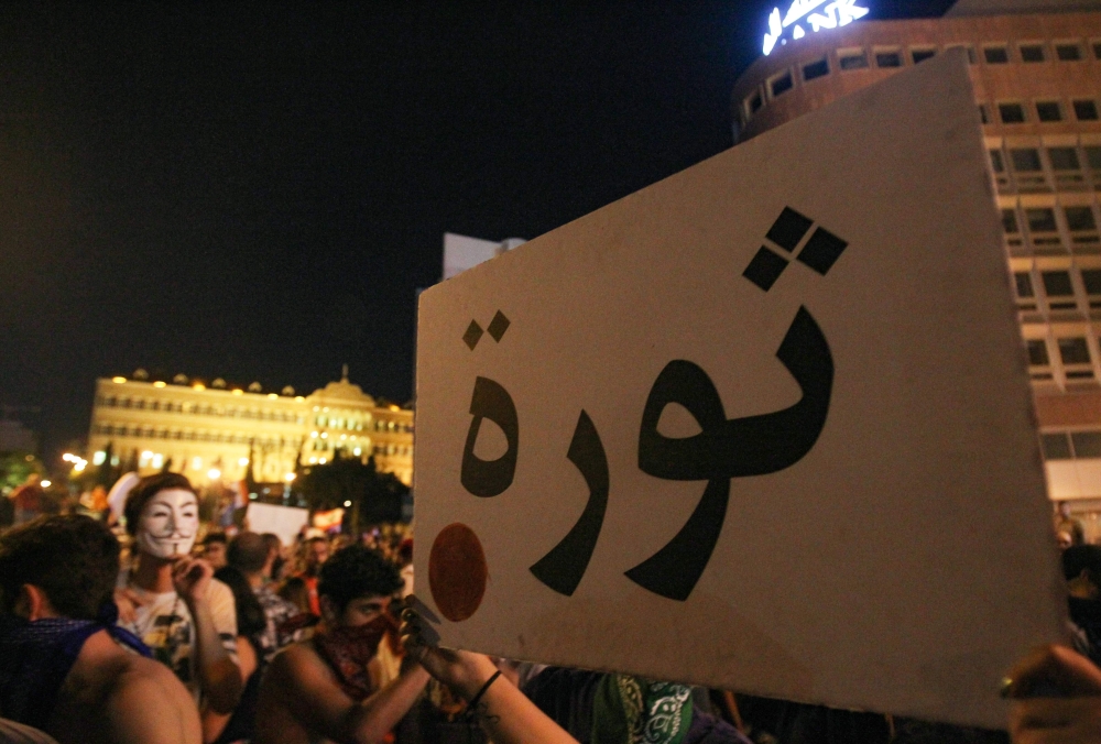 A Lebanese protester lifts a placard that reads 