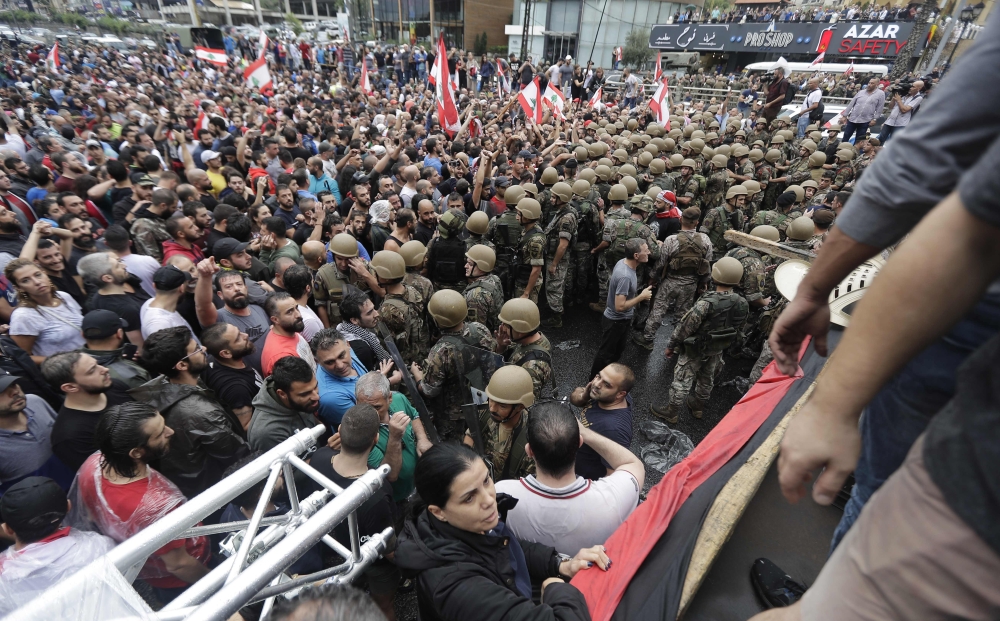 Lebanese protesters stand facing army soldiers after they deployed on major intersections to remove roadblocks set up by demonstrators on October 23, 2019, in the area of Zouk Mosbeh north of the capital Beirut. AFP / JOSEPH EID