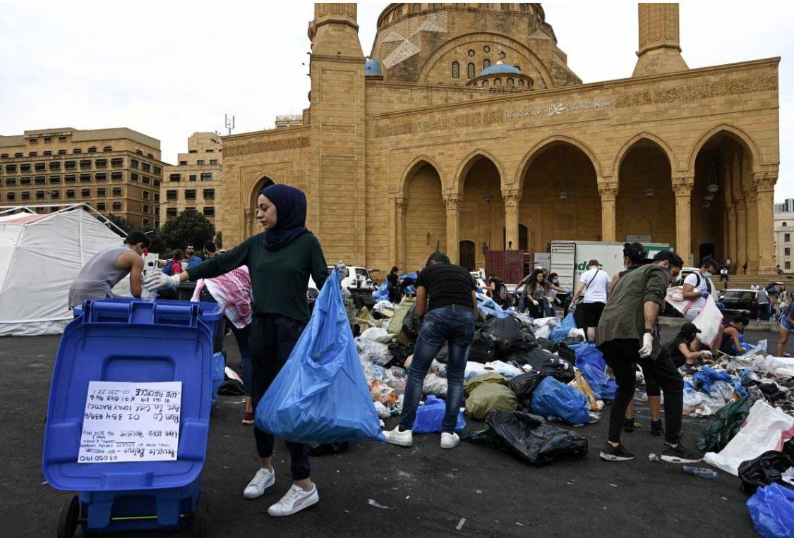 A young woman sorts recycling into a bin in front of the Mohammad al-Amin mosque in Beirut, Lebanon on 23 October 2019. Thomson Reuters Foundation/Finbar Anderson