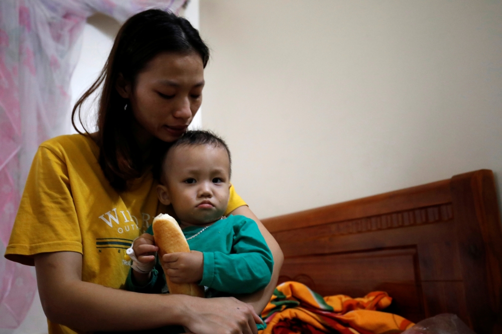 Hoang Thi Thuong, wife of Nguyen Dinh Tu, a Vietnamese suspected victim in a truck container in UK, holds her son Nguyen Dinh Dan at their home in Nghe An province, Vietnam October 26, 2019. REUTERS/Kham