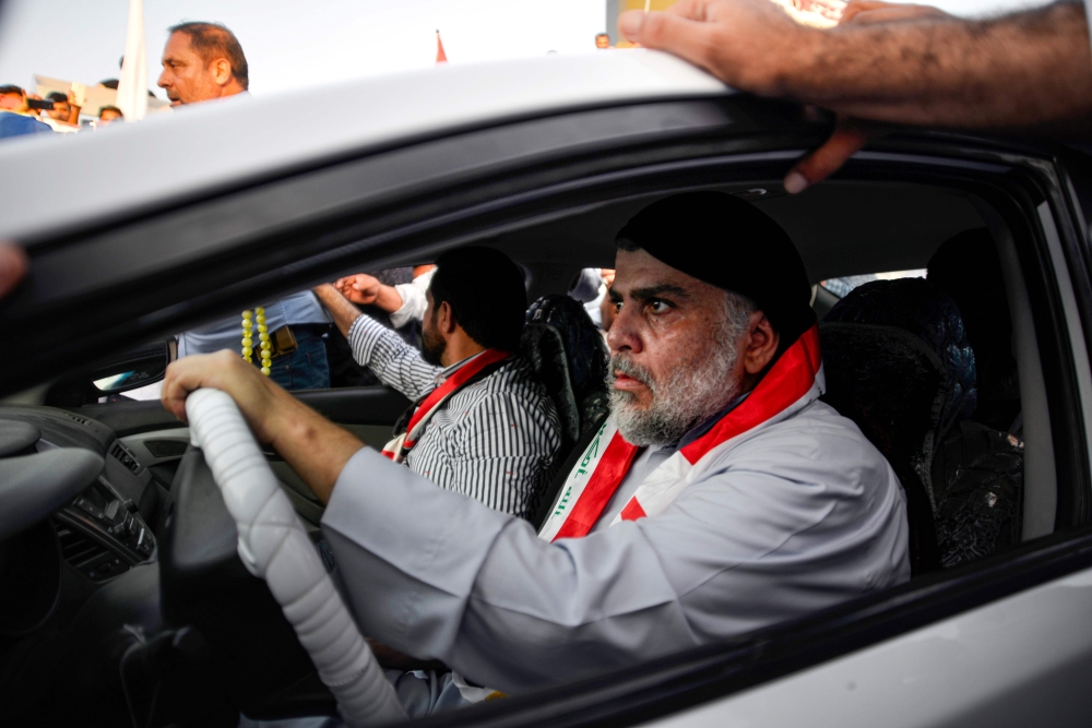 Iraqi Shiite cleric Moqtada al-Sadr (R) drives a car as he joins anti-government demonstrators gathering in the central holy city of Najaf on October 29, 2019.  AFP / Haidar HAMDANI