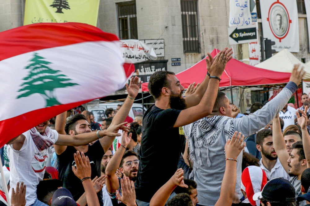 Lebanese anti-government protesters celebrate the resignation of Prime Minister Saad Hariri in the southern city of Sidon on October 29, 2019 on the 13th day of anti-government protests. AFP / Mahmoud Zayyat 