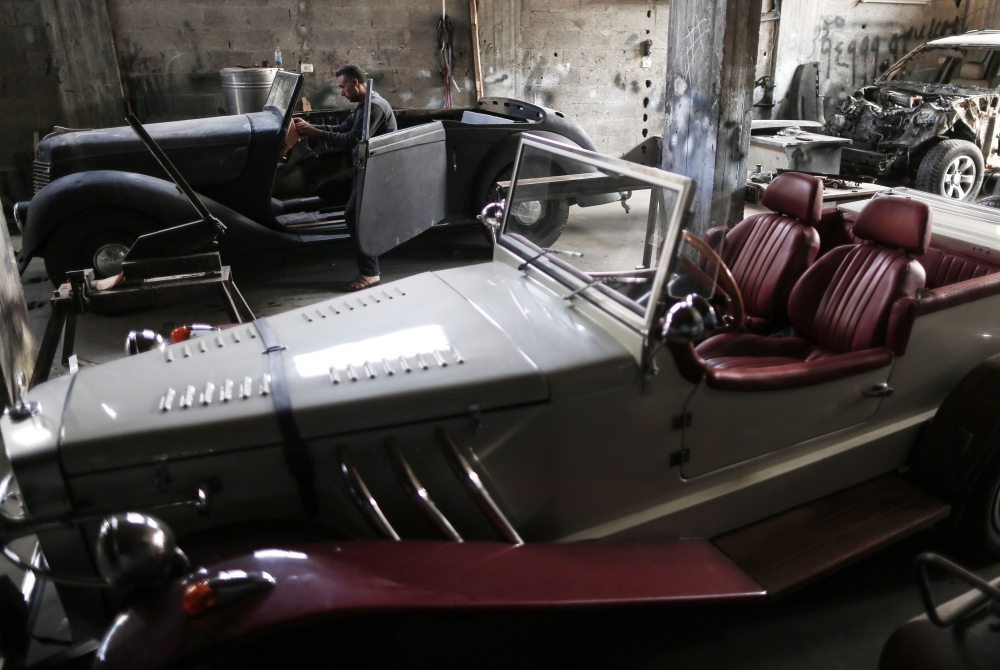 Munir Shindy, a 40-year-old Palestinian who restores old cars as a hobby, works on vintage cars at his workshop in Gaza City on October 28, 2019. AFP / Mahmud Hams
 