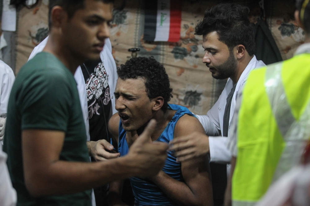 Iraqi paramedics aid an injured protester following clashes with security forces on al-Ahrar bridge in the capital Baghdad during ongoing anti-government demonstrations on November 4, 2019. AFP / Ahmad Al-Rubaye
 