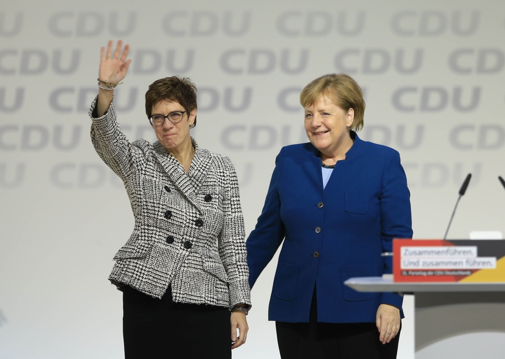 Annegret Kramp-Karrenbauer greets delegates while she stands next to Angela Merkel after she has been elected as new CDU party leader in Hamburg on December 7, 2018. Abdülhamid Ho?ba? / Anadolu Agency
