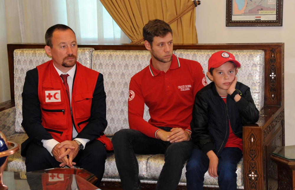 A handout picture released by the official Syrian Arab News Agency (SANA) on November 7, 2019, shows 11-year-old boy Alvin (R) at a meeting to hand him over to representatives of the International Federation of Red Cross and Red Crescent Societies (IFRC) 