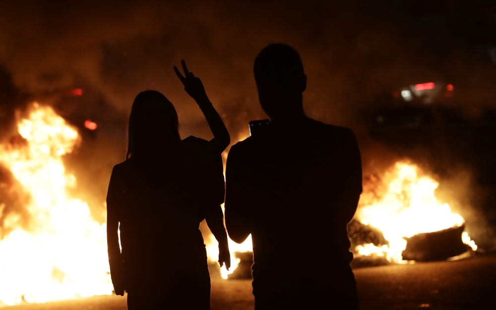 Lebanese anti-government protesters burn tires as they block the main highway linking the city of Tripoli to Beirut at the coastal city of Byblos, north of the capital on November 13, 2019.  / AFP / Joseph EID 