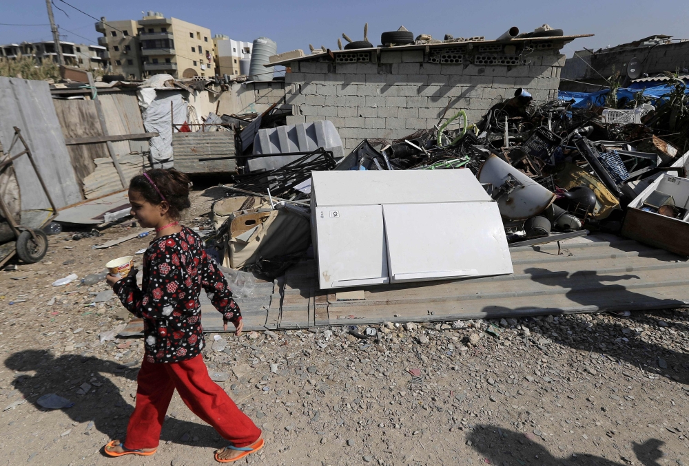 A Lebanese child walks past scrap metal for recycling at an impoverished neighbourhood in al-Mani area of the port city of Tripoli, north of Beirut, on November 7, 2019. AFP / JOSEPH EID