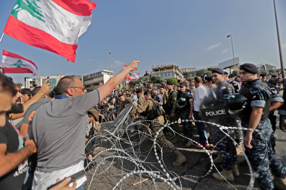 Lebanese demonstrators try to remove the barbed-wire and metal rail, placed by anti-riot police, on the road leading to the Presidential Palace in Baabda, on the eastern outskirts of Beirut on November 13, 2019, nearly a month into an unprecedented anti-g