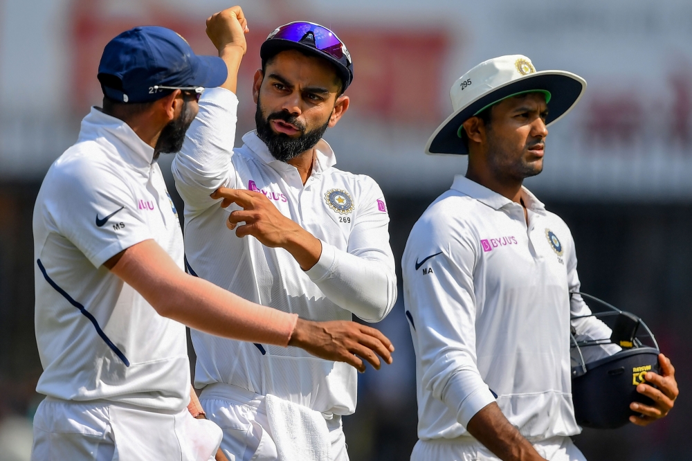 India's Mohammed Shami (L) talks with captain Virat Kohli (C) and teammate Mayank Agarwal looks on as they walk to the pavilion for lunch during the third day of the first Test cricket match of a two-match series between India and Bangladesh at Holkar Cri