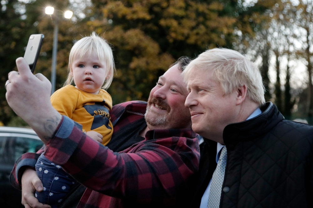 Britain's Prime Minister Boris Johnson poses for a selfie photograph with a member of the public during a General Election campaign trail stop at Thornton-Cleveleys railway station in north-west England on November 15, 2019. AFP / POOL / Frank Augstein