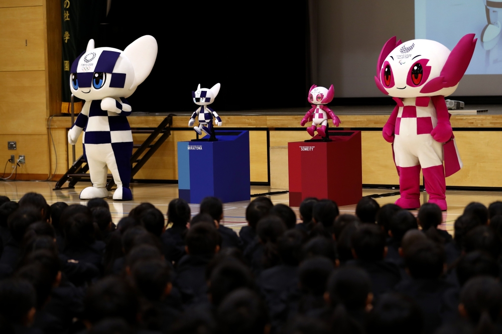 Tokyo 2020 Olympic and Paralympic Games' mascots and robot-type mascots Miraitowa (L) and Someity (R) attend a ceremony at Hoyonomori elementary school in Tokyo on November 18, 2019.  / AFP / Behrouz MEHRI 