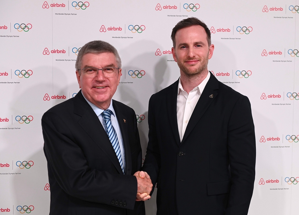 International Olympic Committee (IOC) President Thomas Bach (L) and Airbnb co-founder Joe Gebbia shake hands at an event in London to announce Airbnb as a leading partner of the Olympics on November 19, 2019. AFP / Daniel Leal-Olivas 