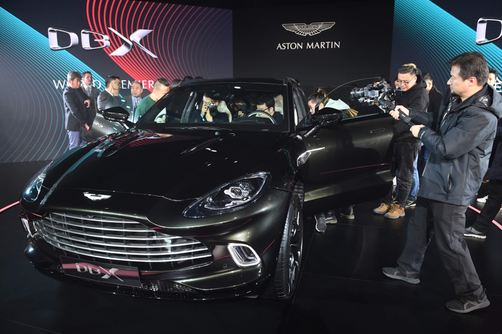 Journalists and guests look at the Aston Martin DBX SUV at its world premiere in Beijing on November 20, 2019. Aston Martin launched its first ever SUV in the Chinese capital on November 20. / AFP / GREG BAKER