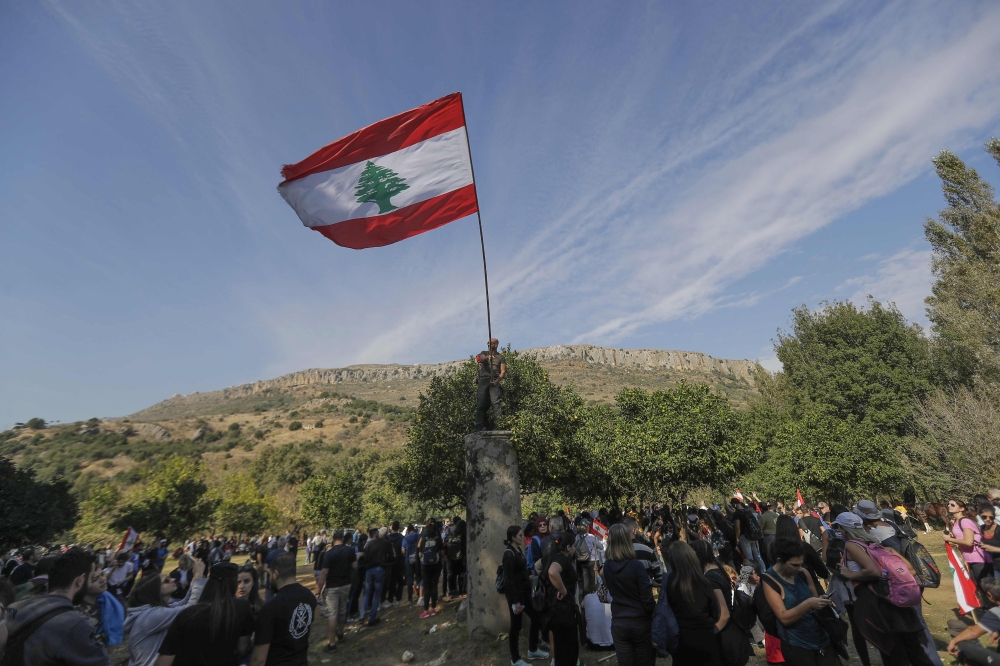 Lebanese protesters raise a national flag as they take part in a 20km (12 miles) march in the Bisri Valley, southwest of the capital Beirut on November 22, 2019, to protest against the construction of a dam in the area. AFP / JOSEPH EID