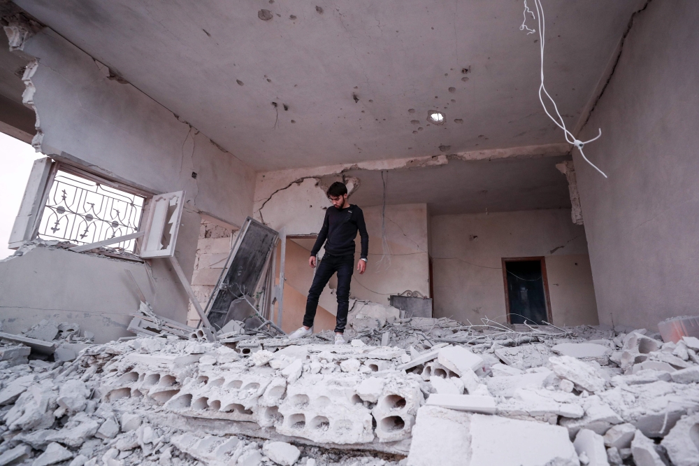 A Syrian youth walks through rubble and debris in a building that was damaged by a reported government forces' air strike in the village of al-Haraki in the northwestern Idlib province on December 1, 2019. / AFP / Omar Haj Kadour 