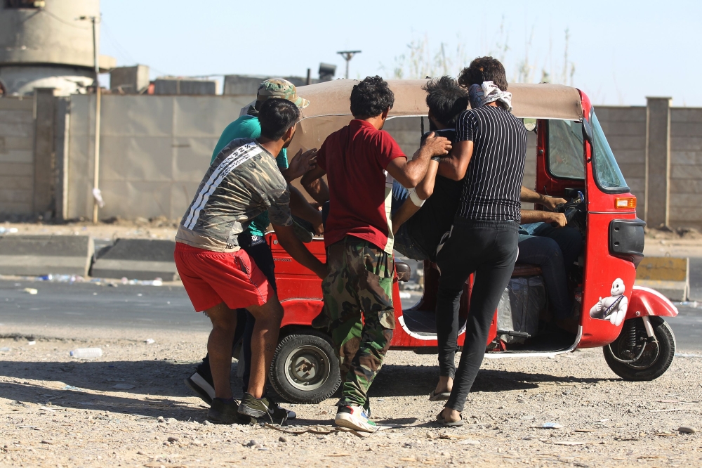Iraqi men carry a wounded protester into a Tuk-Tuk during a demonstration against state corruption failing public services and unemployment in central Khellani Square, Baghdad on October 4, 2019. AFP / Ahmad Al-Rubaye