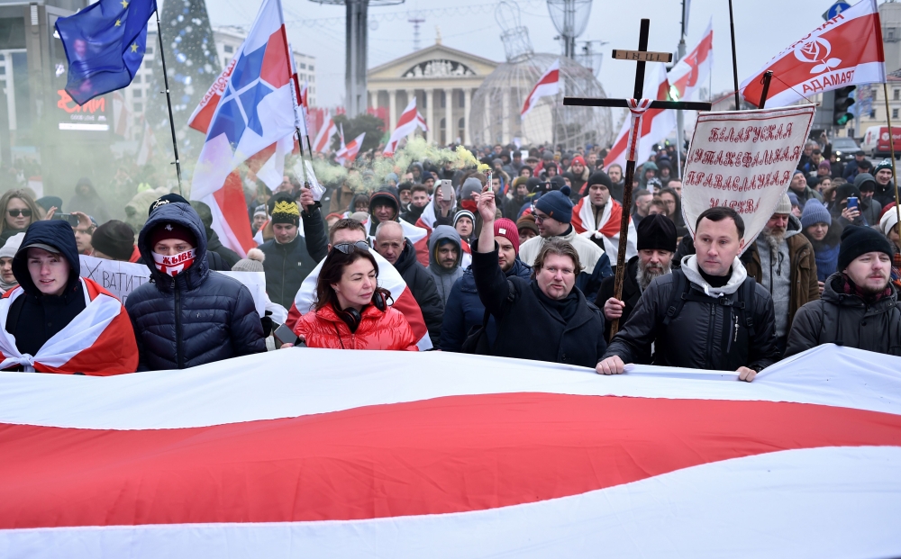 People carry a giant historical Belarusian white-red-white and anti-integration banners as they attend an opposition rally against a Belarusian-Russian integration project in Minsk, on December 7, 2019.   AFP / Sergei GAPON
