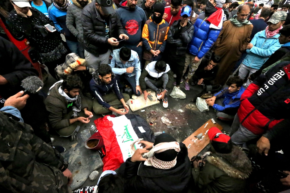 Iraqi protesters mourn and pray at the site where 17 people at least were killed and dozens more wounded overnight at Al-Khilani square in the capital Baghdad, amid ongoing anti-government demonstrations on December 7, 2019.  AFP / SABAH ARAR