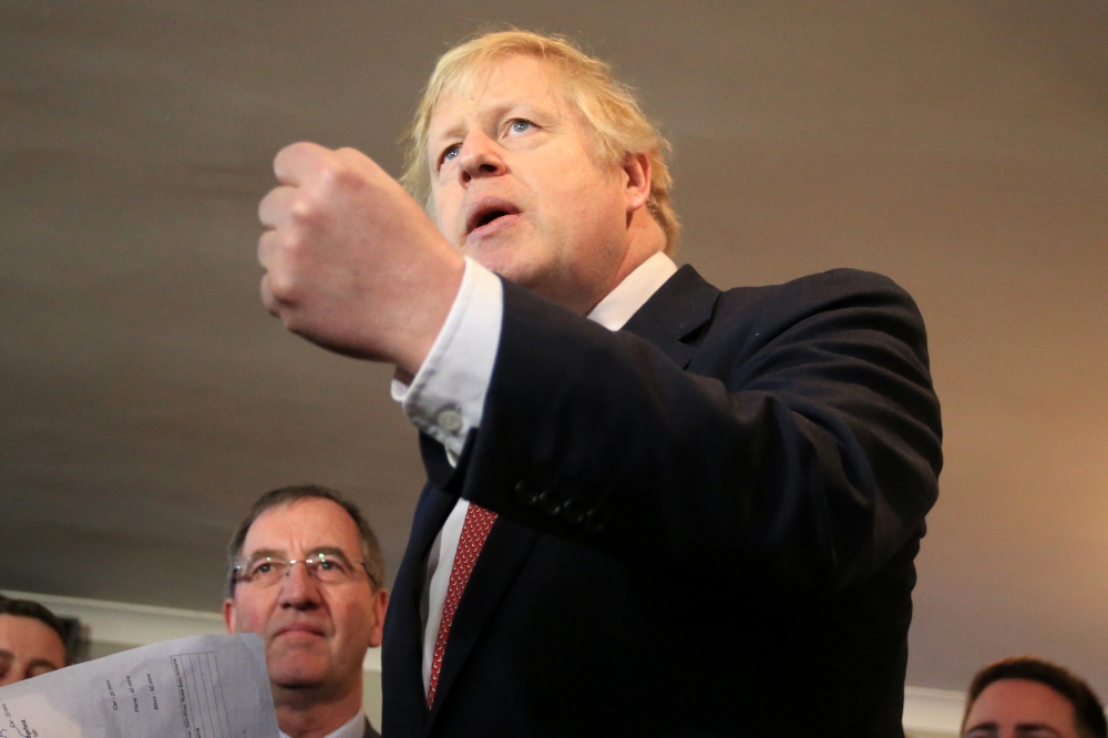 Britain's Prime Minister Boris Johnson gestures as he speaks to supporters on a visit to meet newly elected Conservative party MP for Sedgefield, Paul Howell, at Sedgefield Cricket Club in County Durham, north east England on December 14, 2019, following 