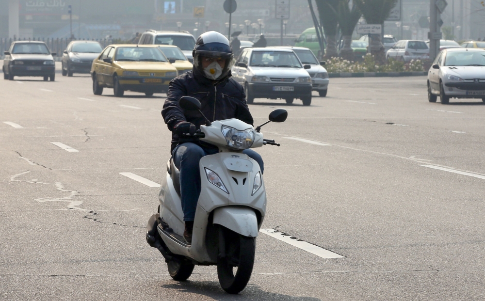 An Iranian motorists wearing a breathing mask while commuting as a blanket of smog covers the city as heavy pollution hit the Iranian capital on December 15, 2019. / AFP 