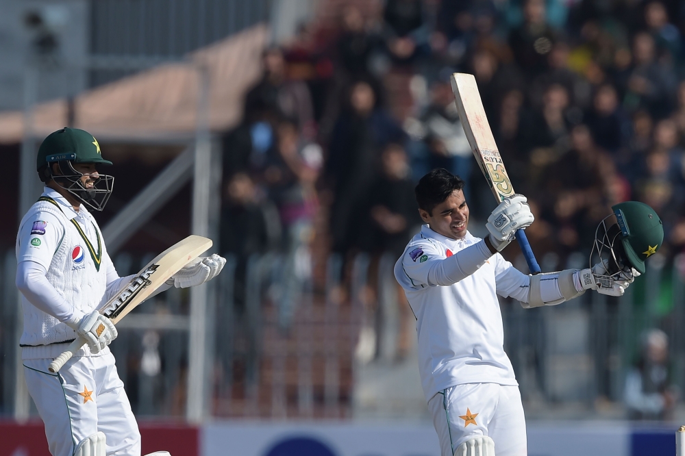 Pakistan's Abid Ali (R) celebrates after scoring half-century (50 runs) as his teammate Pakistan's Azhar Ali applauds during the fifth and final day of the first Test cricket match between Pakistan and Sri Lanka at the Rawalpindi Cricket Stadium in Rawalp